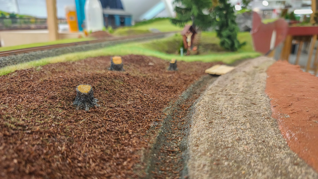 Die Fläche unten der Baümen, der Graben und der Waldweg